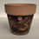 Thumbnail: mini terracotta pot painted brown with trees carved in