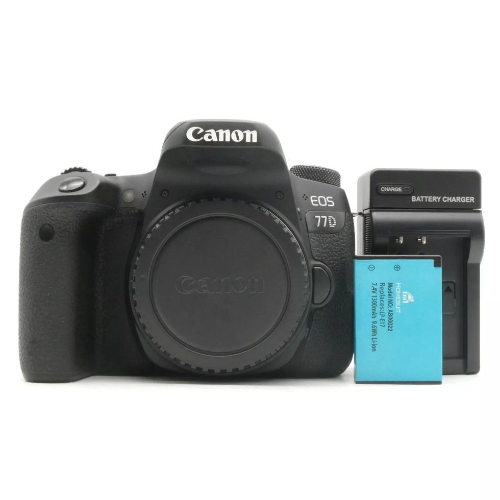 Black Canon camera with battery and charger on white background