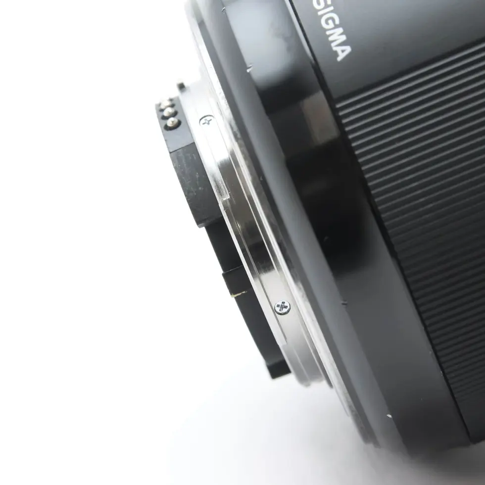 Close-up of a Sigma lens on a white background, showing the lens details.