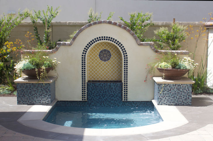 The center piece of the yard is the spa and Spanish Revival inspired deco wall, glass tile pedestals and inset mosaic tile water feature. Precast concrete coping and Caribbean blue pebble finish the look.