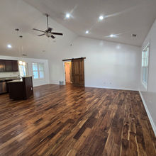 Open living area with wood floors and kitchen beyond