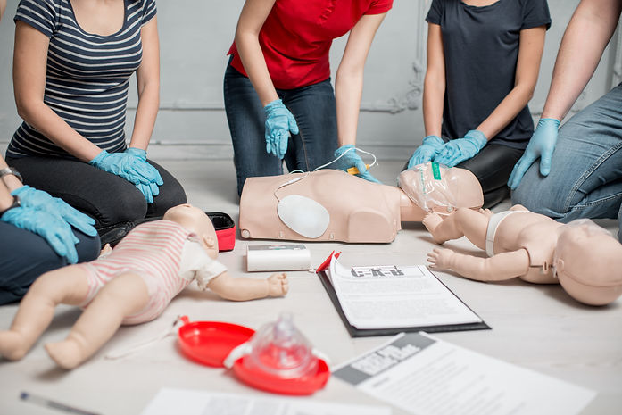 Young woman instructor clinging contacts on a dummy teaching how to make defibrillation du