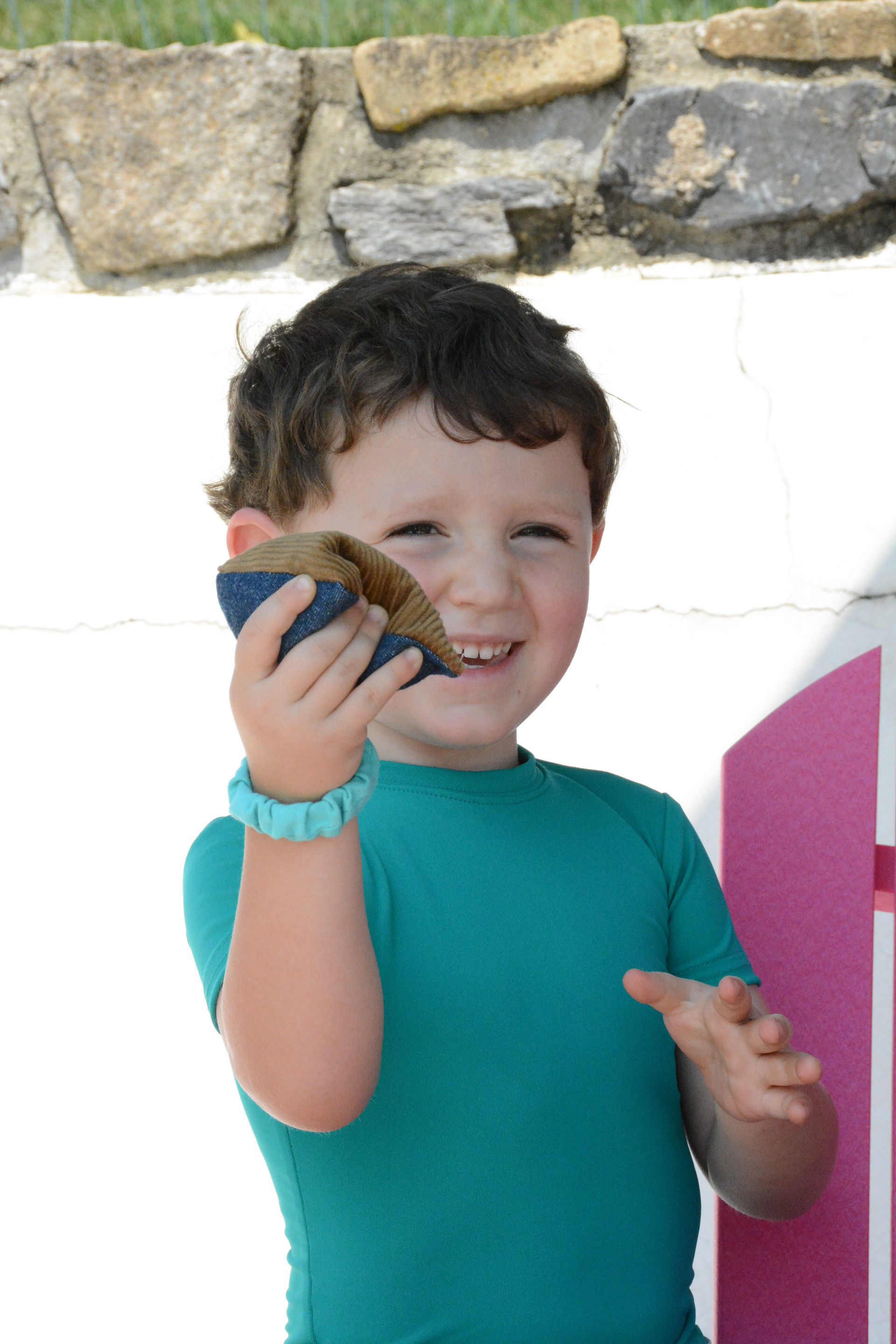 Little boy holding the Kozie Quite-Fun Sensory Fidget Tool wearing the deep green Kozie compression short sleeve shirt
