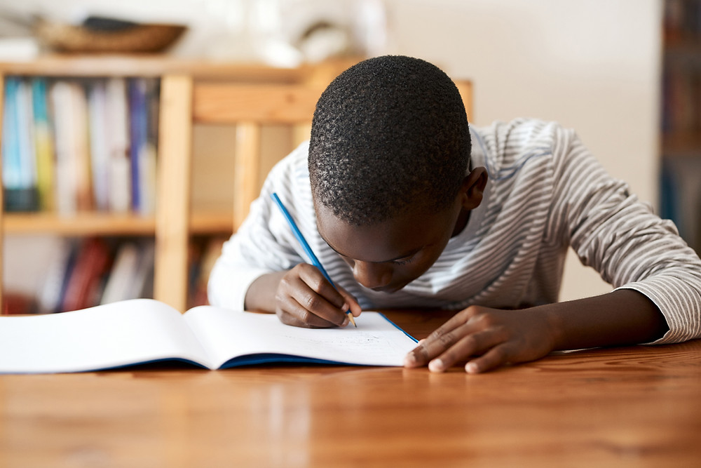 kid writing at table activities for visual sensory system by kozie clothes