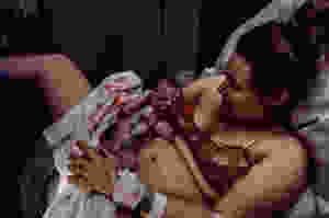 new mother pulls her newborn up to her chest as her son is birthed