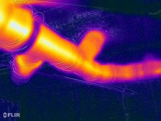 Thermografische opname van een afvoerbuis met stromend warm water, waarbij temperatuurverschillen duidelijk zichtbaar zijn in rood- en oranje tinten.
