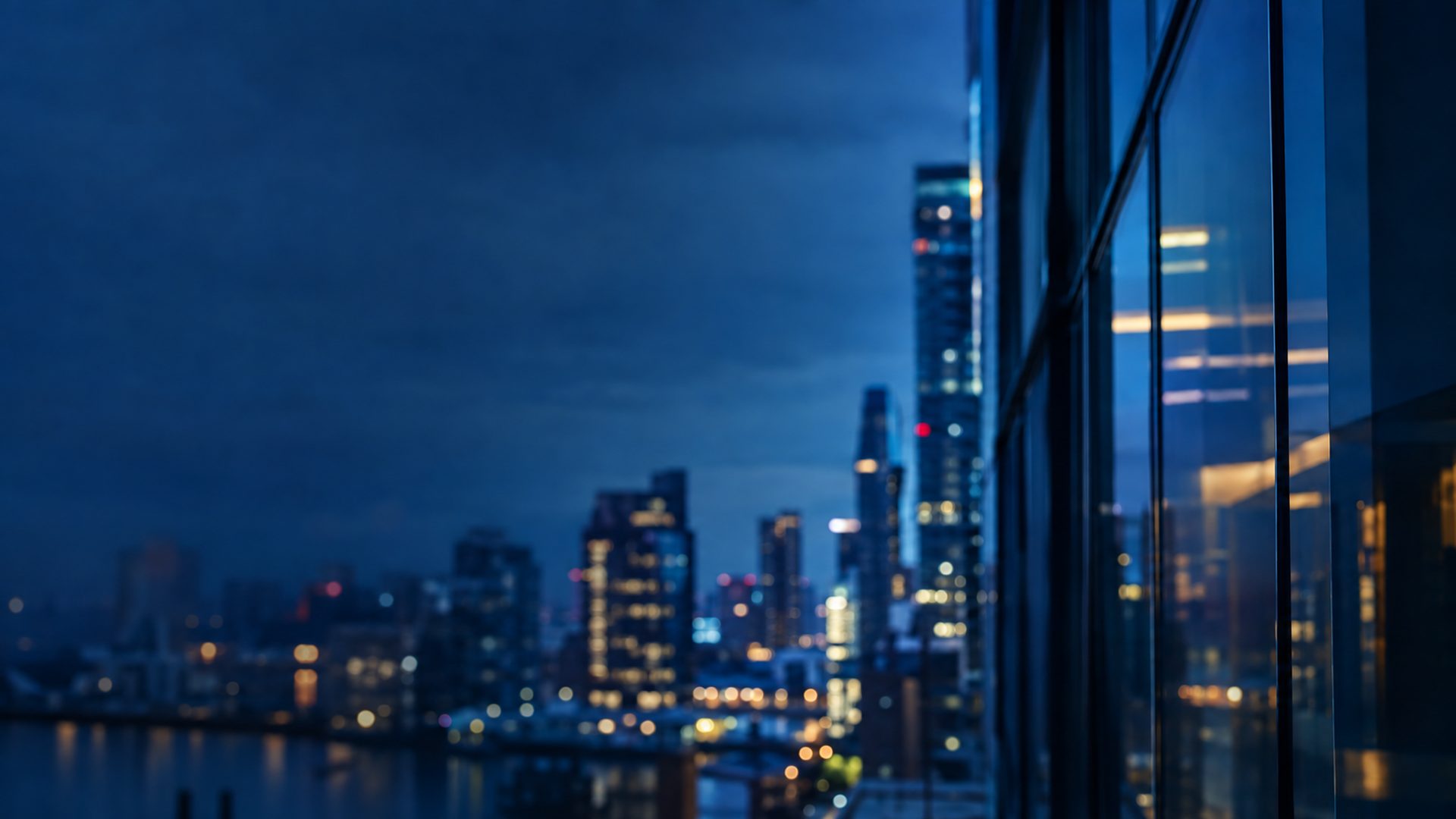 City skyline at night reflected in a modern glass office building