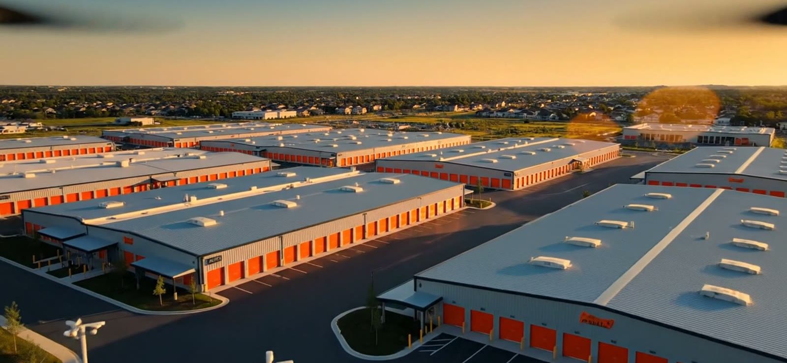 Aerial view of a self-storage facility with rows of storage buildings at sunset