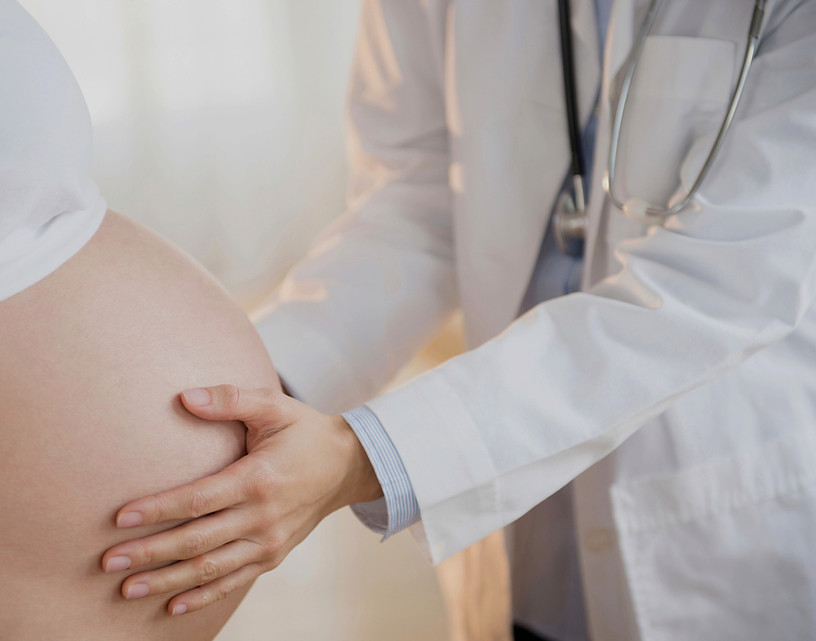 Arzt untersucht Babybauch einer Schwangeren – Impfberatung in der Schwangerschaft