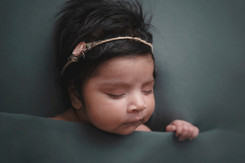 Newborn baby girl laying under a cover