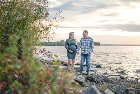 Maternity image of a couple holding hands walking on a beach at sunset