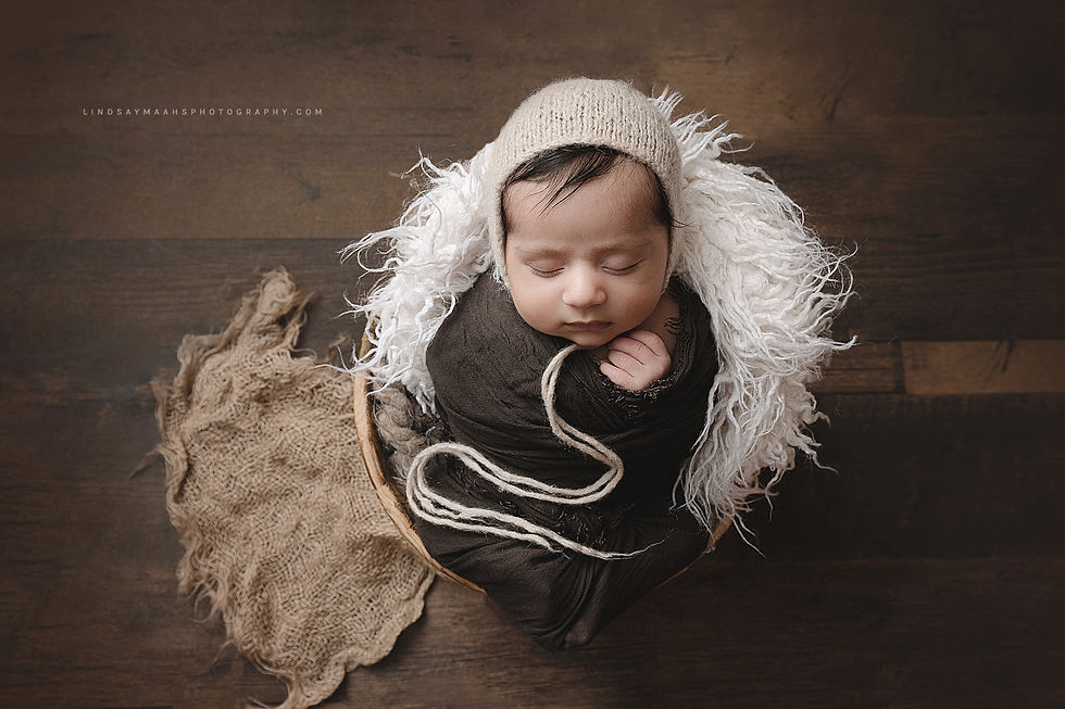 Newborn baby in a basket wearing a bonnet