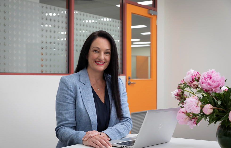 Woman sitting at a desk with computer and pink flowers