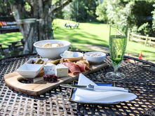 Plate of cheese and condiments on a table with a glass of wine 
