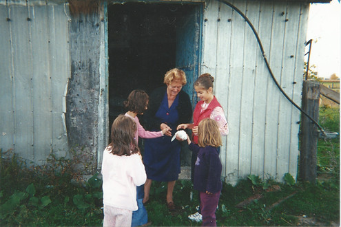 Four girls arounf their great-grandmother, who is holding a white dove for them to pet