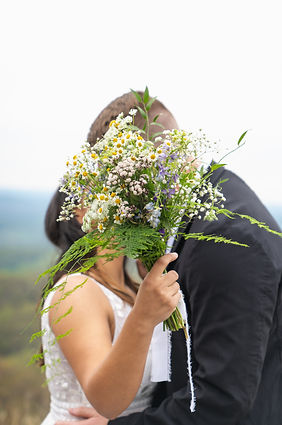 bride and groom kiss behind flower during their mountain elopement