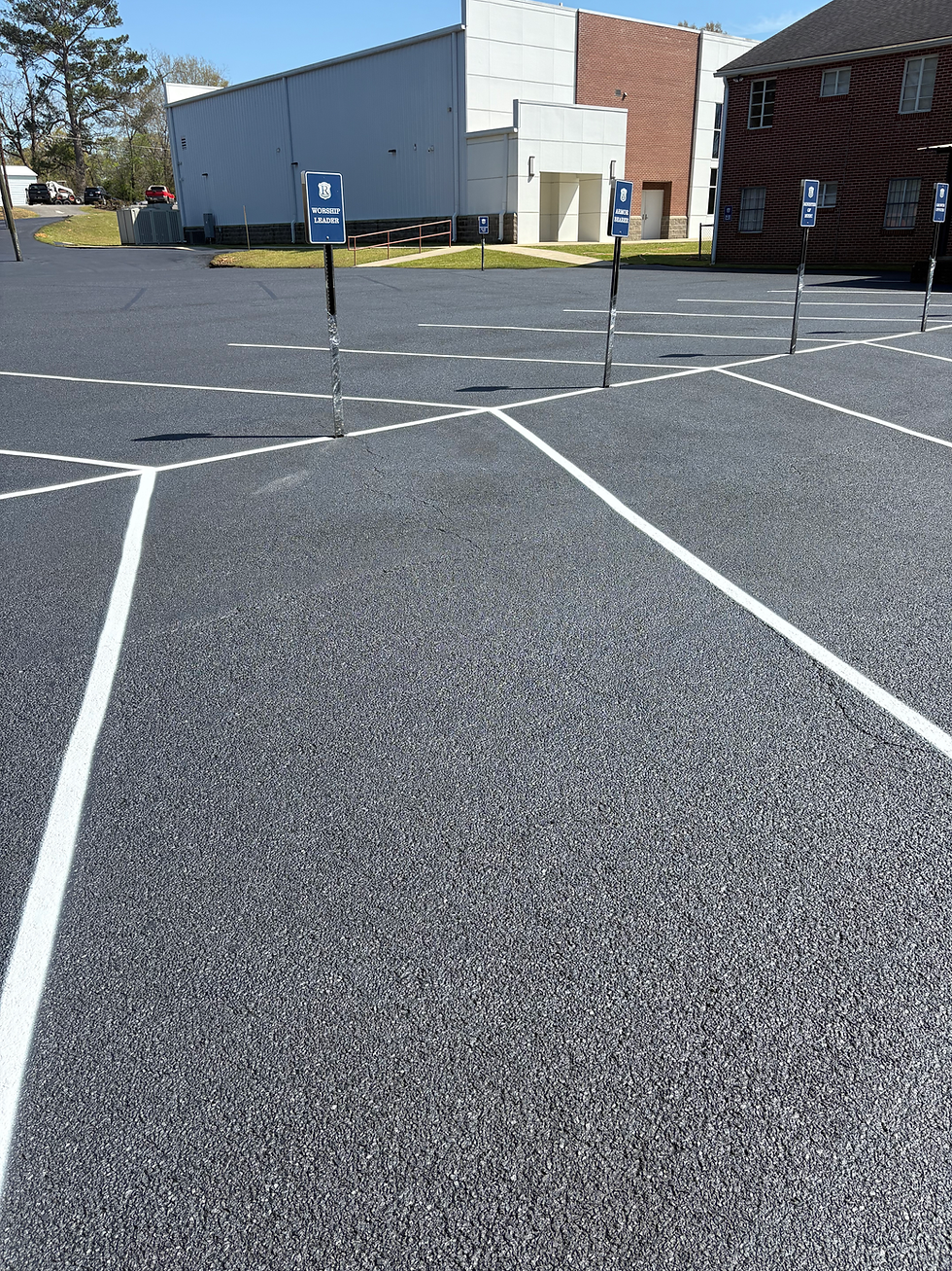 Freshly sealed asphalt paving in a commercial parking lot.