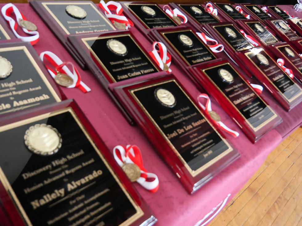 Discovery High School awards ceremony: multiple framed plaques with red ribbons