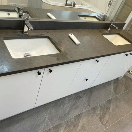 温哥华的现代浴室盥洗台，黑色台面，白色储物柜，简约水龙头，NewHomePro 改造项目。