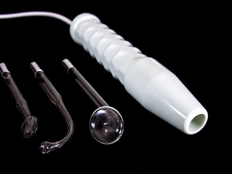 White handheld device with textured grip and three glass attachments on a black background. No text or people are present.