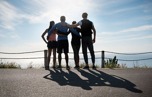 Four friends standing together, arms around each other, appreciating scenic views.