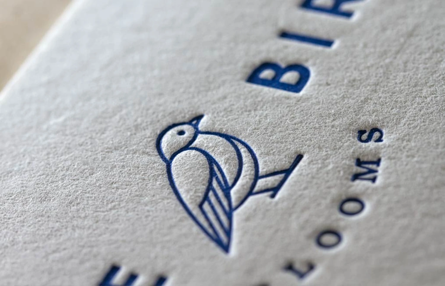 A blue bird graphic and lettering created with a letterpress on thick white stock paper.