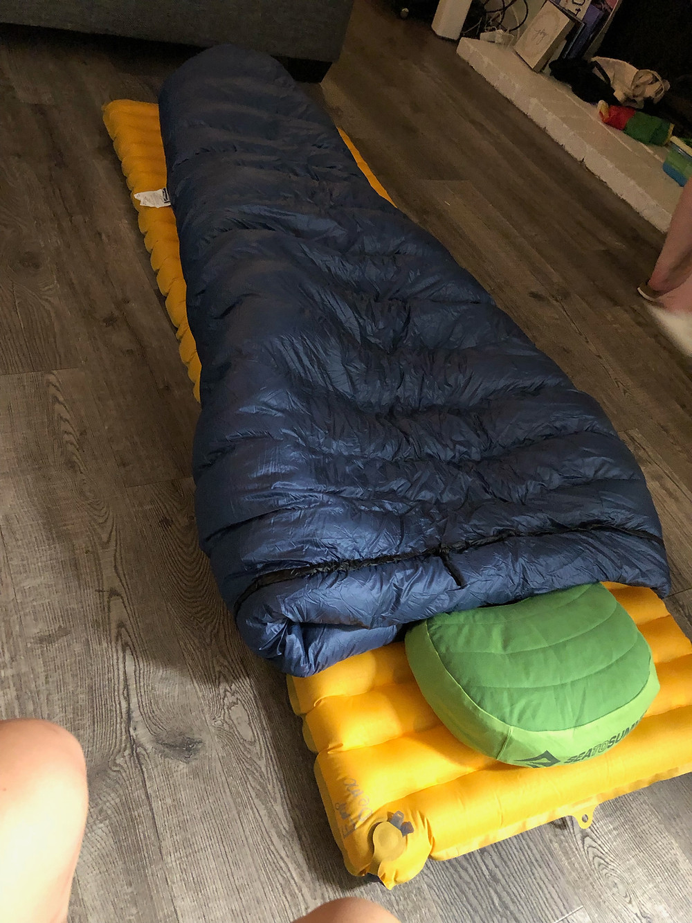 Taylor's sleep setup. Inflatable orange sleeping pad, inflatable green pillow, grey down quilt folded over the top