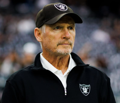 Mike Mayock in Raiders team gear at a stadium.
