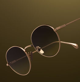 Lunettes de soleil rondes dorées élégantes sur fond brun, design classique.