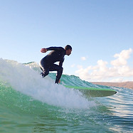 Happy intermediate surfer catching green waves