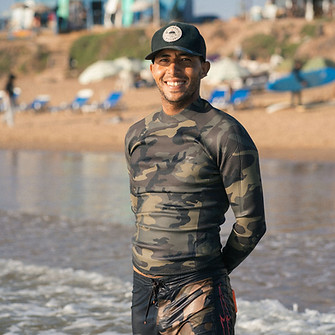 Mehdi head surf coach and founder smiling at the camera by the Moroccan shore
