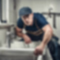 strong plumber wearing a scally cap fixing a sink.jpg
