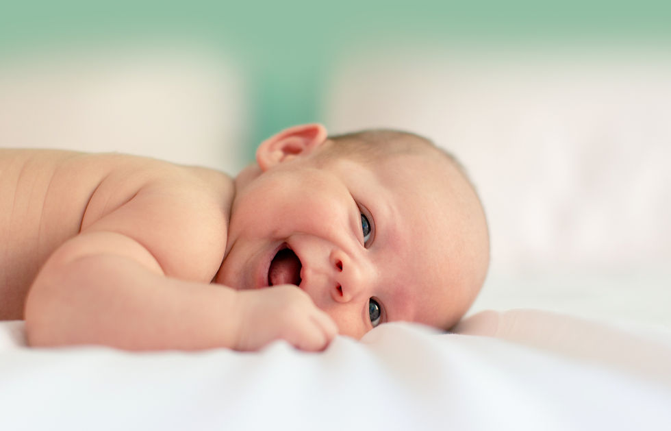 Lachendes Baby im Sommer auf dem Bett