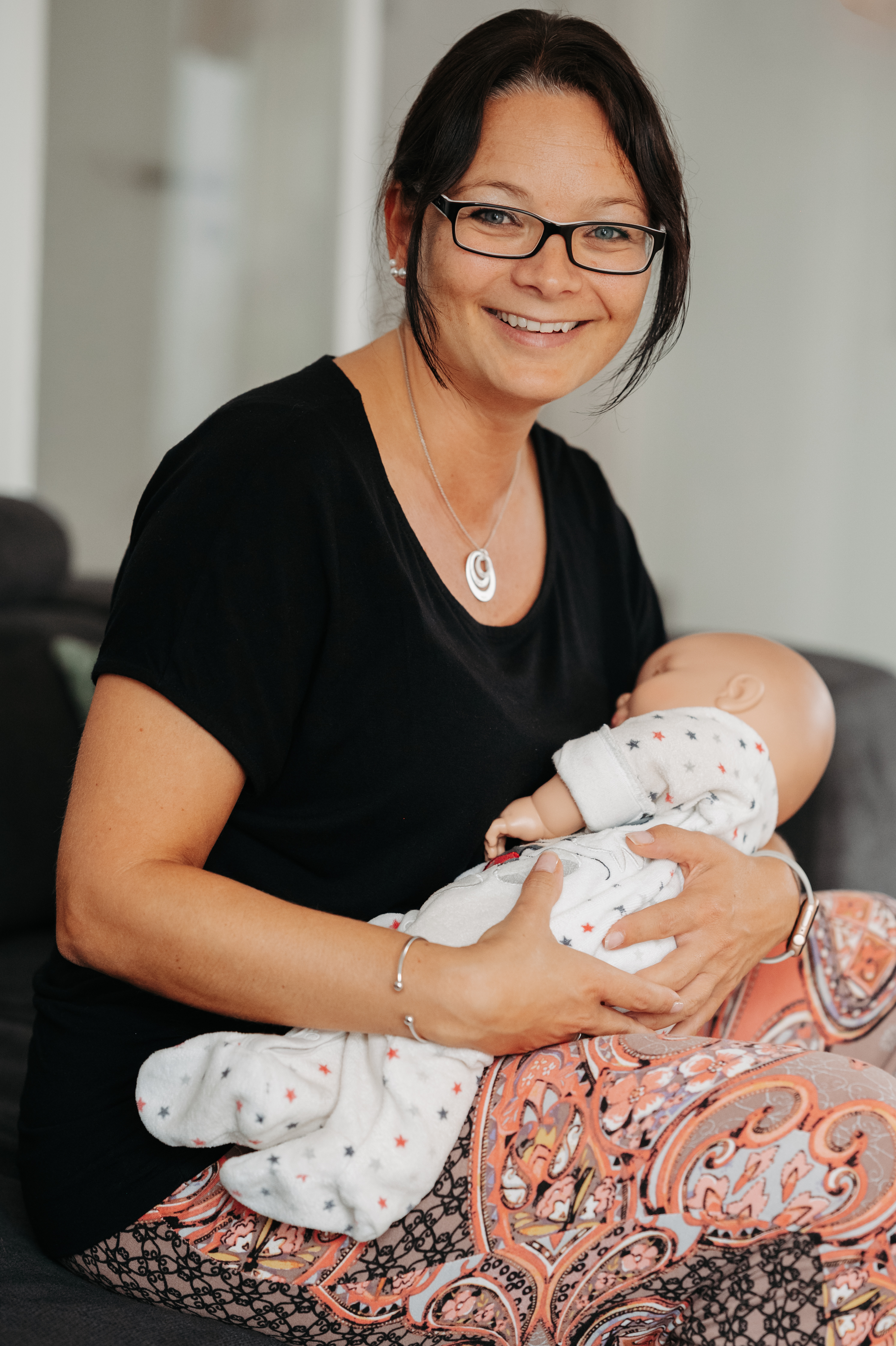 Eine lächelnde Mutter hält ihr friedlich schlafendes Baby im Arm.