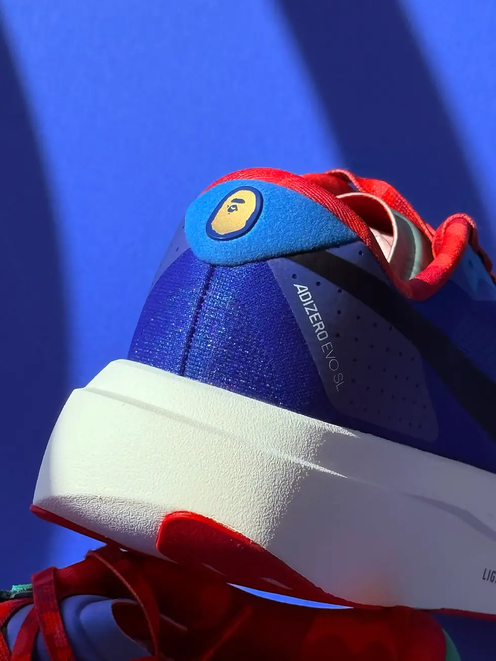 Thumbnail: Adidas X BAPE EVO SL Sneakers in blue, green BAPE APE logo on back of blue shoe