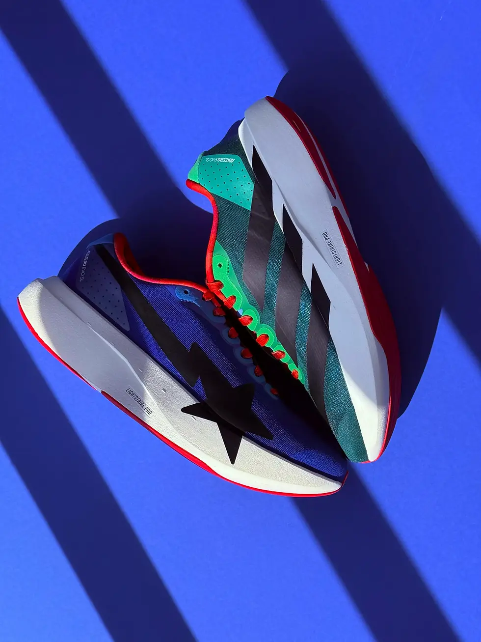 Adidas X BAPE EVO SL Sneakers in blue, green pair side on blue background with shadow stripes