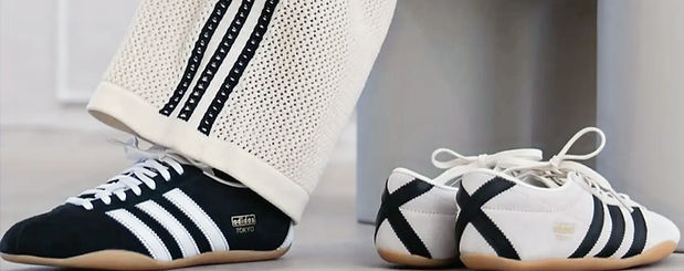 Woman wearing Adidas off-white knit pants and Adidas Black Tokyo Sneakers with 3 white stripes