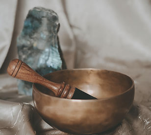 Gold Tibetan bowl for sound healing on gold texture with labradorite and quartz crystals