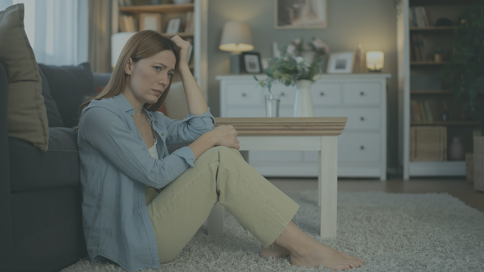 Woman sitting quietly by a window reflecting while experiencing chronic stress and emotional disconnection.