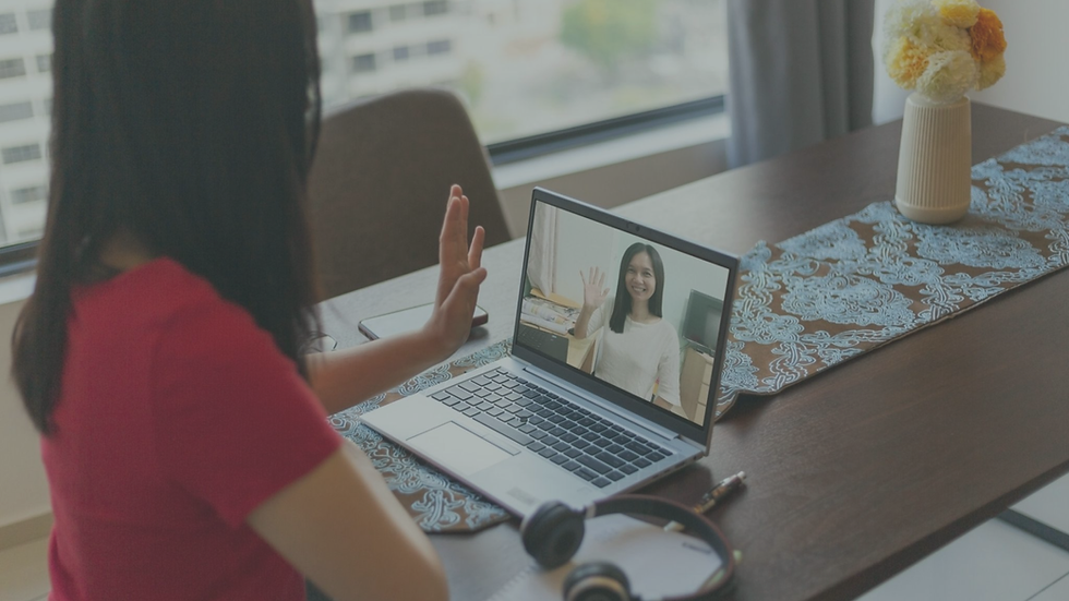 Person participating in a virtual therapy session while taking notes and actively discussing personal goals with a therapist.