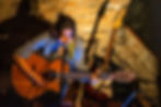 Musicienne chantant et jouant de la guitare acoustique aux Concerts 2025 à la Boîte à Meuh.