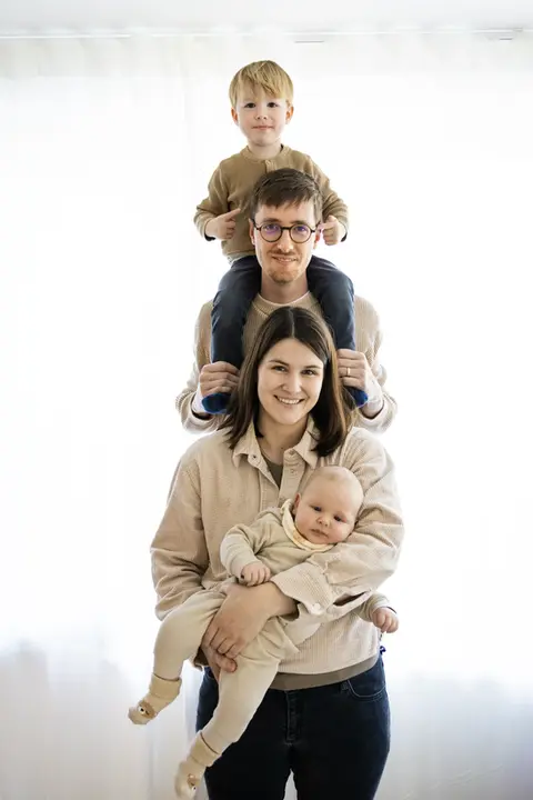Familien Fotoshooting bei dem eine vierköpfige Familie aufgereiht hintereinander steht. Der große Bruder sitzt auf den Schultern des Papas.