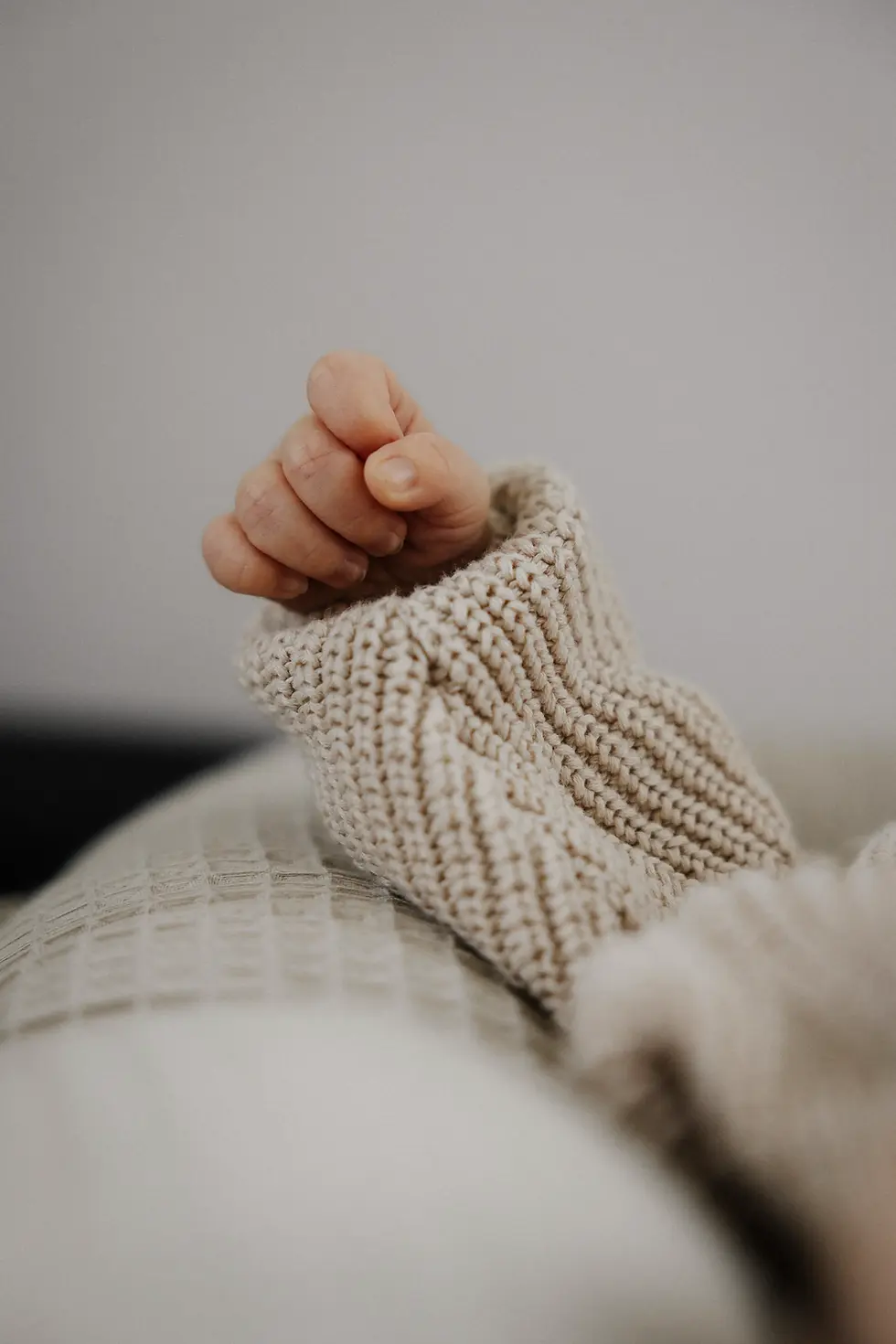 Newborn Shooting bei dem die Hand eines Babys zu sehen ist. Es hat einen Strickpulli an.