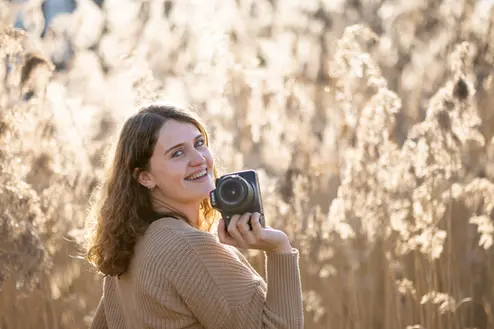 Fotograf dreht sich über Schulter und hält in einer Hand die Kamera. 
