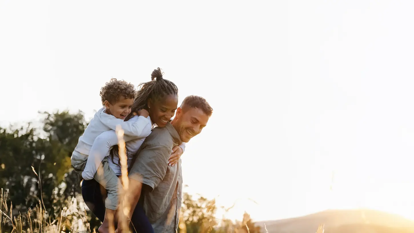 Familien Fotoshooting mit einem kleinen Sohn. Die Frau sitzt auf dem Rücken des Mannes und der Sohn auf dem Rücken der Mama