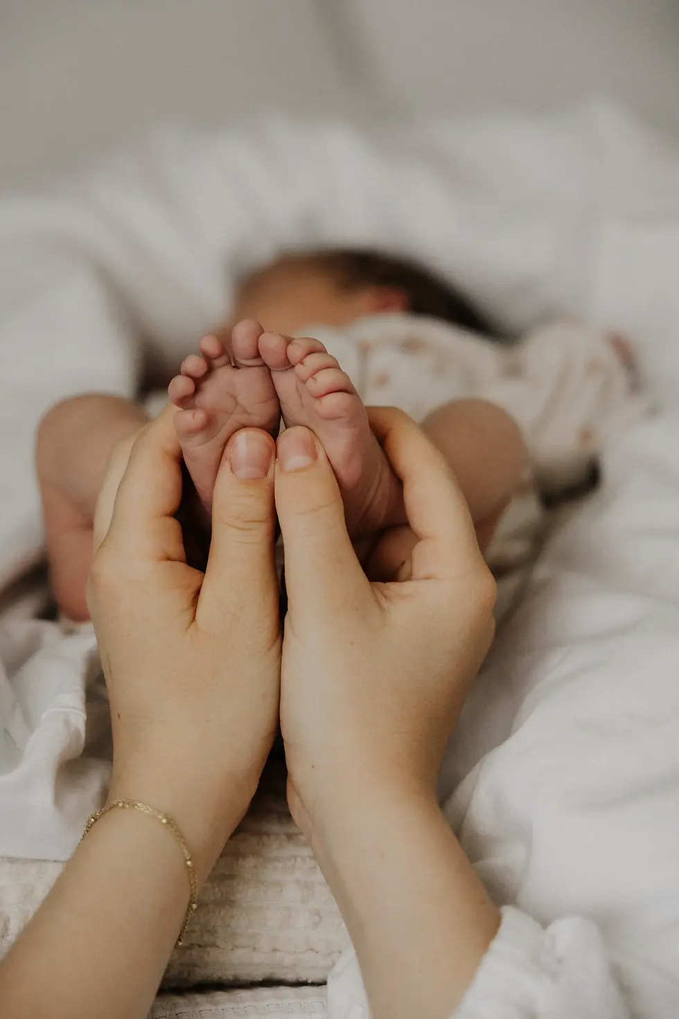 Newborn Shooting bei dem die Füße des Kindes von der Mama gehalten werden.
