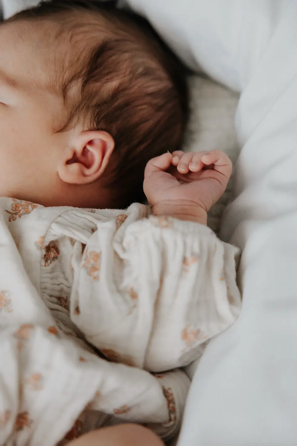 Man kann auf den Fotos von dem Newborn Shooting nur den halben Kopf, das Ohr und den Arm des babys erkennen, das in einem weißen Nest liegt,
