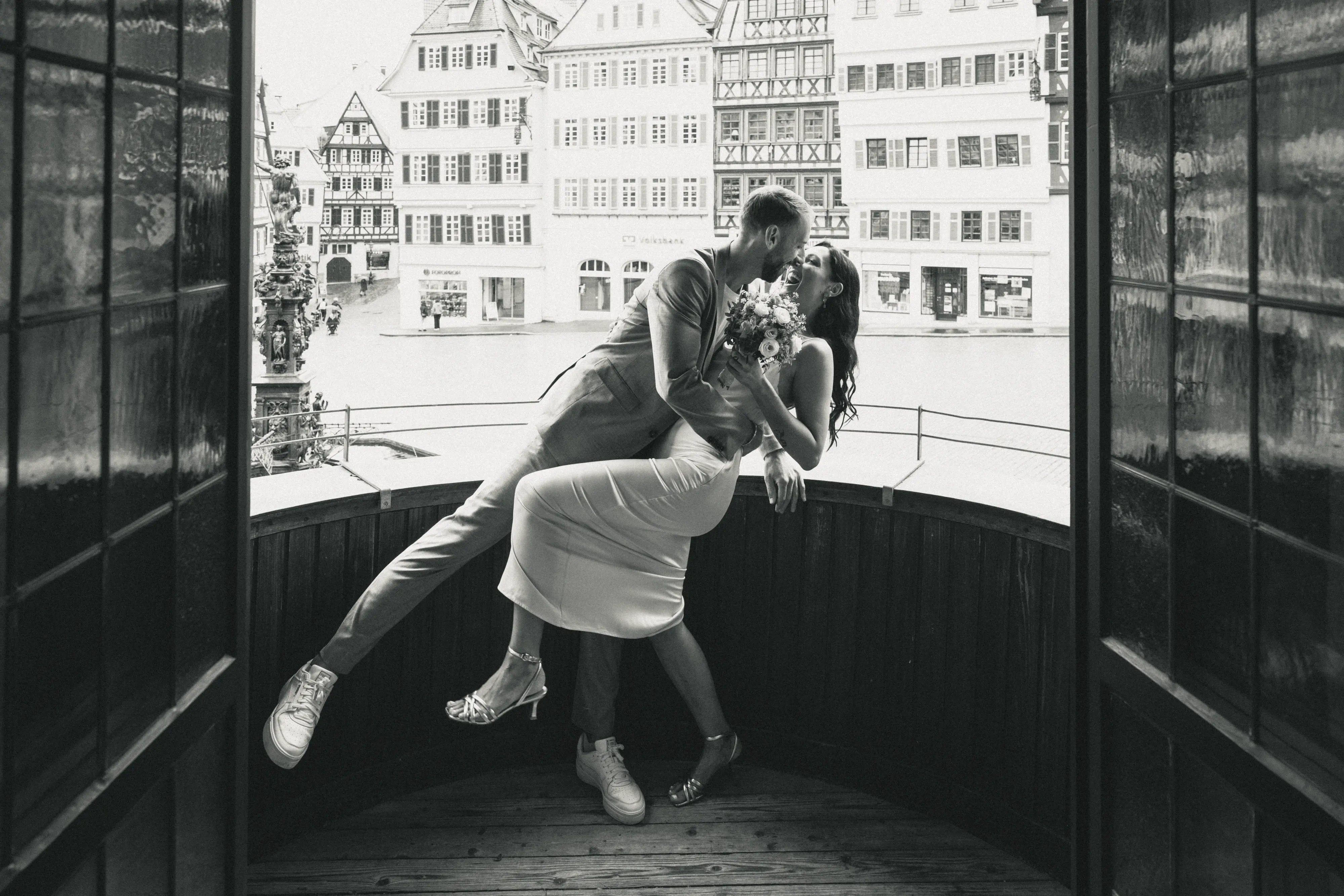 Hochzeitsfotos von einem Brautpaar beim Standesamt, die auf einem Balkon sich feierlich küssen.