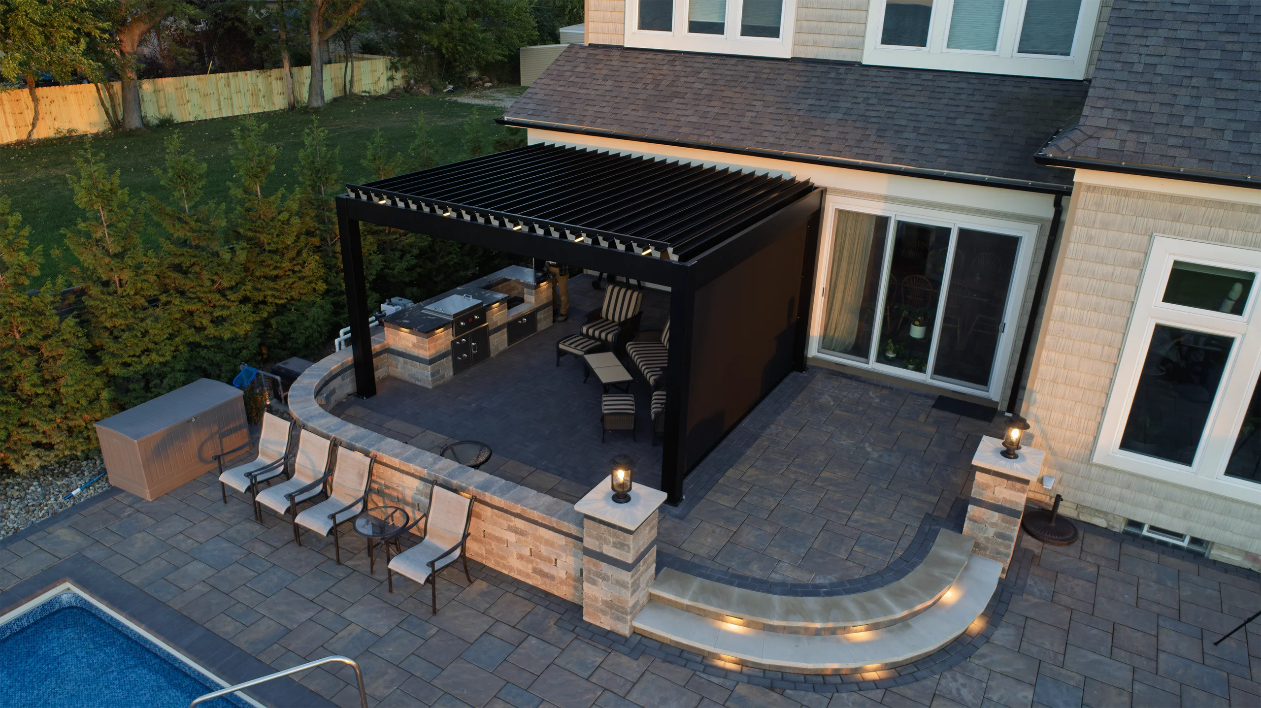 Motorized aluminum louvered pergola poolside on a luxury outdoor living space with a pool by Lake Erie.