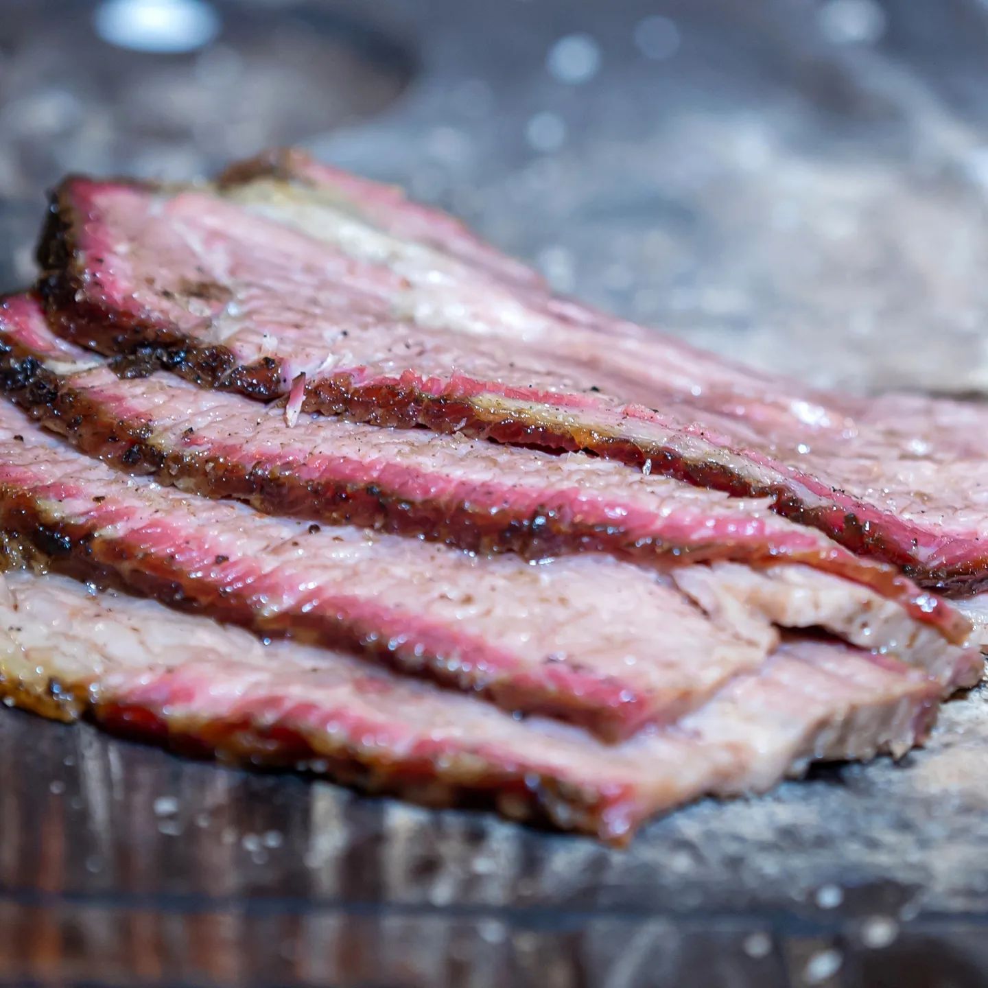 Smoked to perfection! Slices of succulent brisket, expertly arranged on a rustic wooden board.